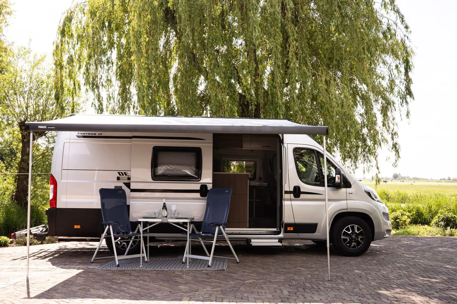 Hobby Vantana K65 ET Deluxe van opzij met luifel, open schuifdeur en twee stoelen