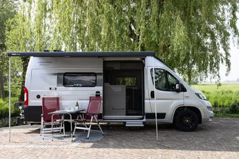 Karmann Mobil Davis Lifestyle 600 van opzij met luifel, open schuifdeur en stoelen